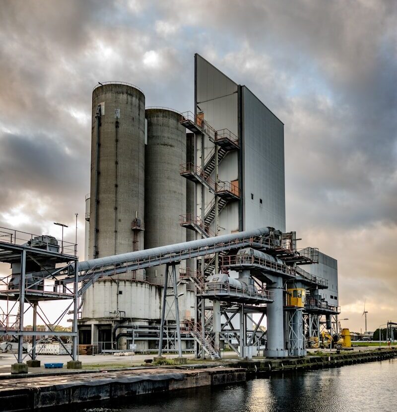 a large industrial building next to a body of water